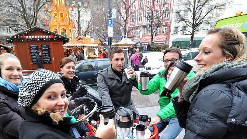 Feierfreunde prosten sich zu und fahren auf einem Glühweinbike durch München Feierfreunde prosten sich zu und fahren auf einem Glühweinbike durch München