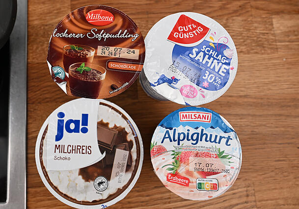 Produkte der Eigenmarken von Rewe (ja!), Aldi (Milsani), Lidl (Milbona) und Edeka (gut & günstig) stehen in einer Küche auf einer Arbeitsplatte. Die vergleichbaren Eigenmarken-Produkte kosten in jedem Supermarkt gleich viel, wie die SWR-Reportage zeigt.