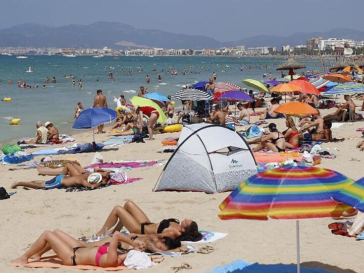 Touristen sonnen sich am Strand von El Arenal, einem der Hauptziele für deutsche und niederländische Touristen während der Sommersaison.