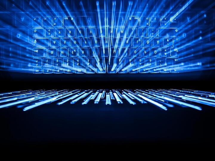 Die beleuchtete Tastatur eines Laptops spiegelt sich im Bildschirm.