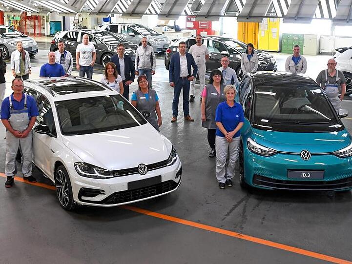 Mitarbeiter des VW-Werks in Zwickau posieren neben einem Golf Variant (l) und einem ID.3.
