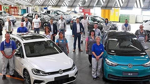 Mitarbeiter des VW-Werks in Zwickau posieren neben einem Golf Variant (l) und einem ID.3.