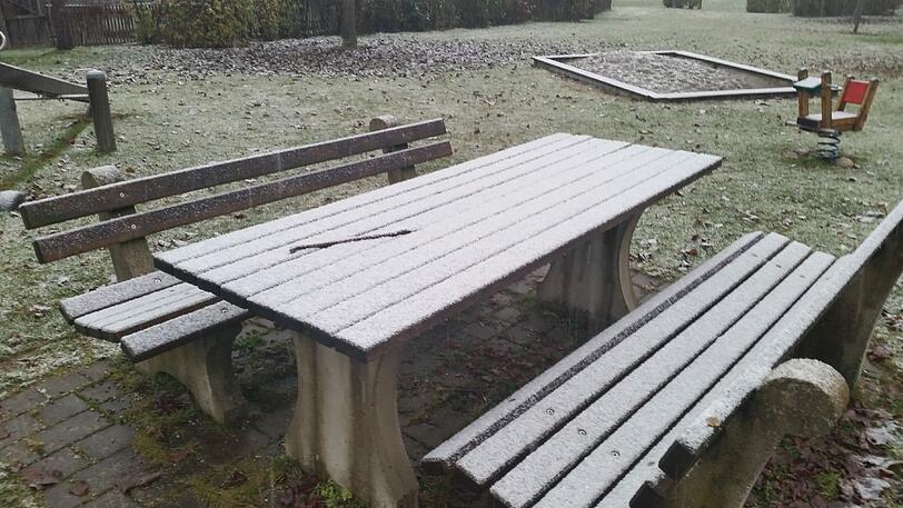 Eine dünne Schneeschicht auf dem Holztisch