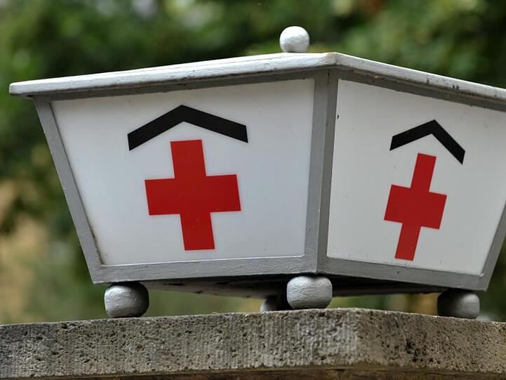 Ein Rote Kreuz vor einem Klinikum. Foto: Martin Schutt/Archivbild