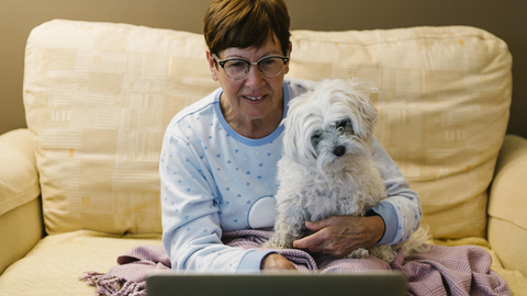 Eine Frau sitzt mit ihrem Hund vor dem Laptop. Durch Online-Termine beim Tierarzt sind Kunden sehr flexibel.