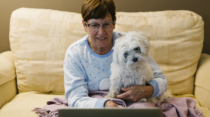 Eine Frau sitzt mit ihrem Hund vor dem Laptop. Durch Online-Termine beim Tierarzt sind Kunden sehr flexibel.