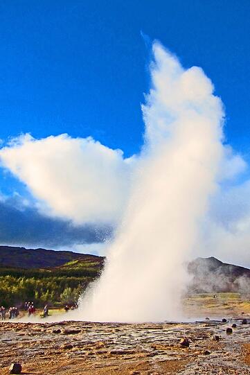 Geysir Strokkur, das Butterfass. Wind weht die Fontaene zur Seite.