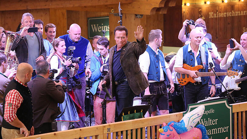 Erst eine kühle Maß, danach Dirigieren auf der Bühne: Die Bilder vom Schwarzenegger-Besuch im Schützen-Festzelt.