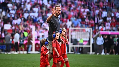 Münchens Harry Kane geht mit Kindern nach dem Spiel auf dem Spielfeld.