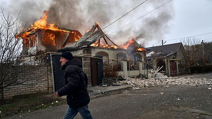 Ein Anwohner läuft an einem brennenden Haus in Cherson vorbei, das nach ukrainischen Angaben bei russischem Beschuss am orthodoxen Weihnachtsabend getroffen wurde.