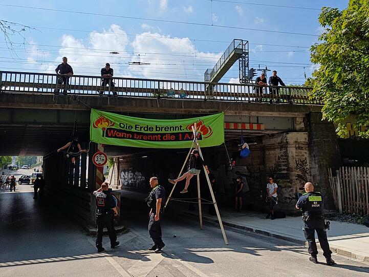 Die Aktivisten entrollen ein Plakat an einer Eisenbahnbrücke in Sendling.