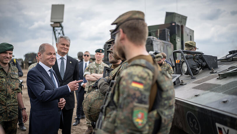 Im Gespräch mit deutschen Soldaten: Bundeskanzler Olaf Scholz (Mitte) neben Daniel Andrä, Bundeswehr-Kommandeur der NATO Enhanced Forward Presence Battle Group (eFP-Bataillon, links) und Gitanas Nauseda, Präsident von Litauen (3.v.l) im Camp Adrian Rohn.