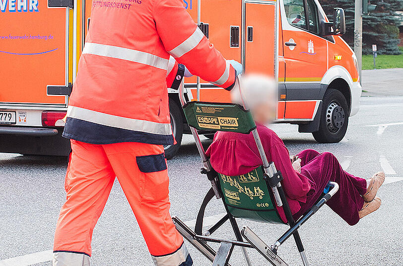 Ein Feuerwehrmann bringt eine Frau zu einem Rettungswagen.