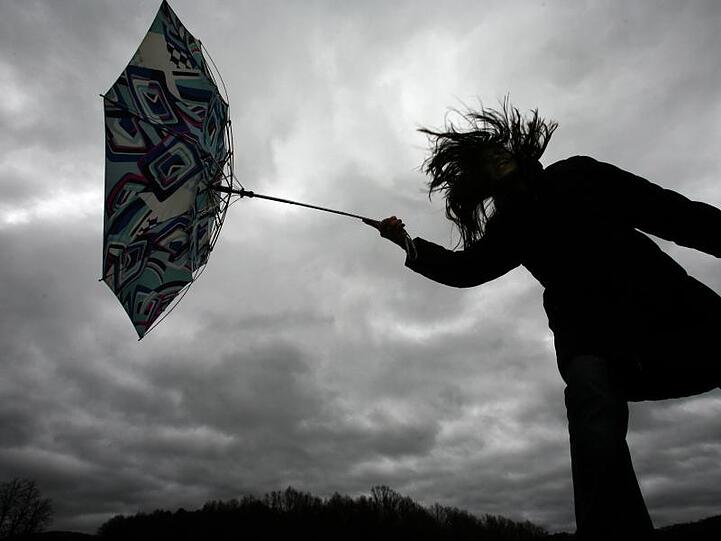 Eine Winböe erfasst den Regenschirm eines Mädchens. Foto: Marcus Führer/dpa/Archivbild