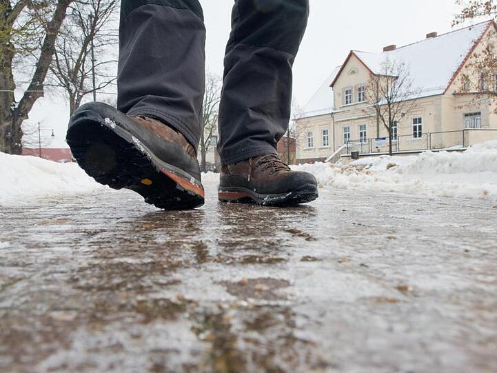 Ein Mann geht auf einem vereisten Gehweg. Foto: Patrick Pleul/Archiv