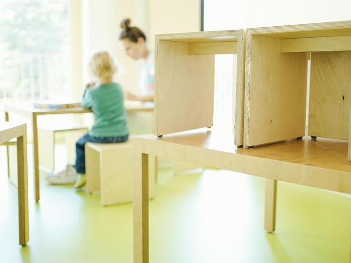 Eine Erzieherin und ein Kind spielen an einem Tisch. Foto: Uwe Anspach/dpa/Archivbild