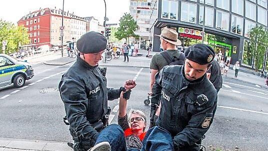 Bayerische Polizisten tragen eine Aktivistin in München nach einer Protestaktion von der Straße. Bayerische Polizisten tragen eine Aktivistin in München nach einer Protestaktion von der Straße.