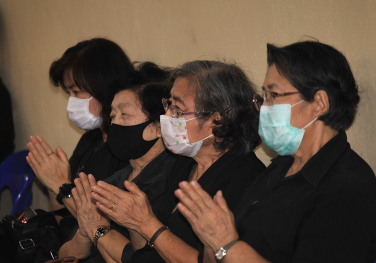 Thailand, Bangkok: Menschen mit Gesichtsmasken nehmen an der Beerdigungszeremonie eines 35 Jahre alten Thailänders teil, der an Dengue-Fieber litt und sich später mit Covid-19 infizierte.