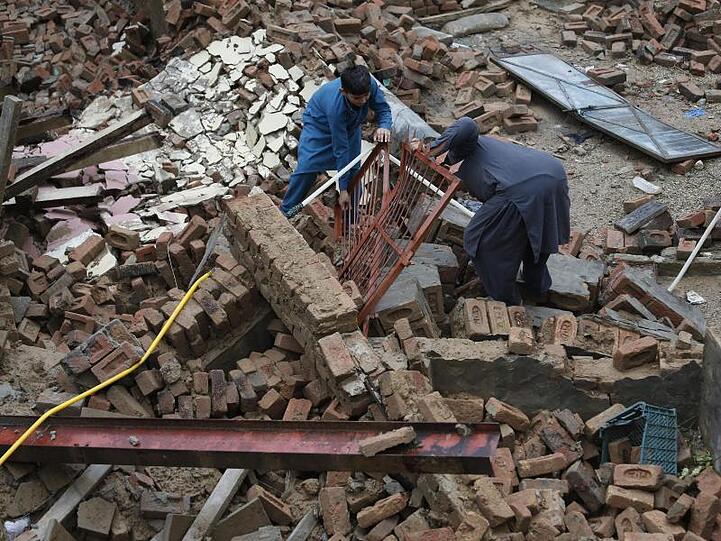 Jungen versuchen, Stücke aus dem Schutt eines Hauses zu bergen, das durch ein starkes Erdbeben im Nordosten Pakistans beschädigt wurde.