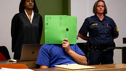 Der wegen Vergewaltigung eines jungen Polen Angeklagte (vorne) sitzt anlässlich des Prozessauftakts im Gerichtssaal vor seiner Rechtsanwältin Rita Drar (l) und einer Justizbeamtin. Der Fall hatte im vergangenen Jahr zu diplomatischen Verwicklungen mit Polen geführt, weil die damalige Regierung die deutsche Migrationspolitik für den Fall verantwortlich machte.
