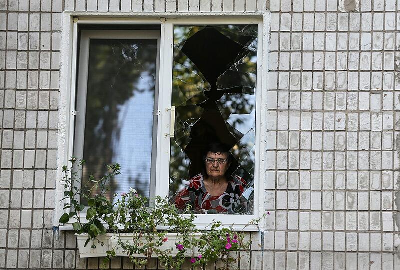 Eine Frau in Donezk schaut nach einem Raketenangriff der ukrainischen Armee durch das Fenster ihrer zerstörten Wohnung.