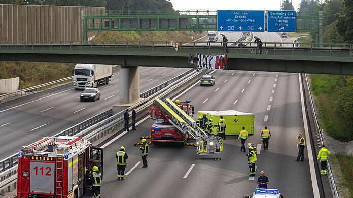 Aktivisten nehmen an einer Banneraktion an einer Brücke über der Autobahn A96 bei Germering teil.