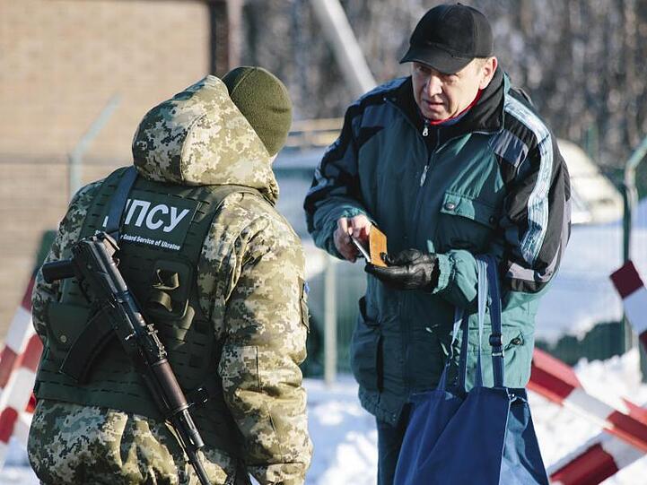 An der ukrainisch-russischen Grenze bei Hoptivka überprüft ein ukrainischer Grenzschutzbeamter die Dokumente eines Mannes.