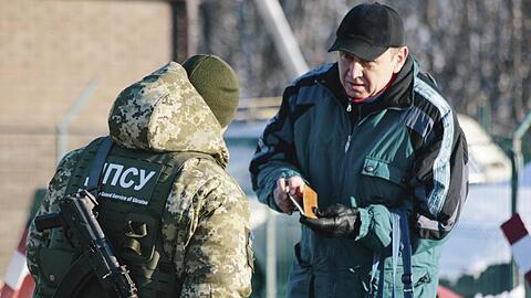 An der ukrainisch-russischen Grenze bei Hoptivka überprüft ein ukrainischer Grenzschutzbeamter die Dokumente eines Mannes.