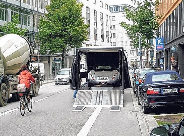 Klassisch Münchnerisch: Ein Transporter lädt einen Sportwagen aus und verstellt dabei den Radstreifen.