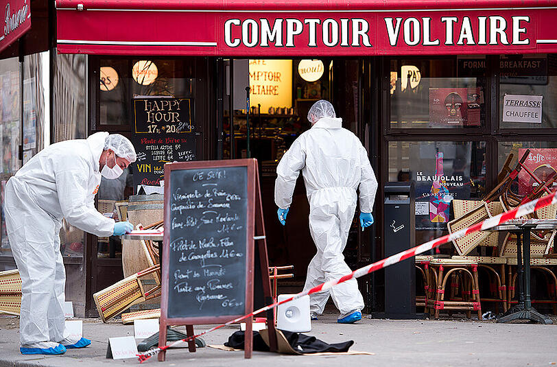 Polizisten in Schutzanzügen sichern am 14.11.2015 vor dem Cafe Comptoir Voltaire in Paris Spuren. Dort hatte sich Ibrahim Abdeslam in der Nacht zuvor in die Luft gesprengt.
