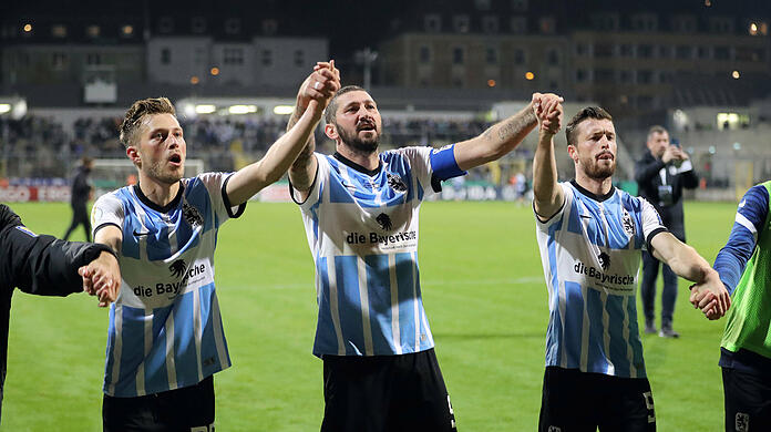 Marius Willsch (l.), Sascha Mölders (m.) und Quirin Moll feiern nach dem Schlusspfiff mit den Fans im Grünwalder Stadion.