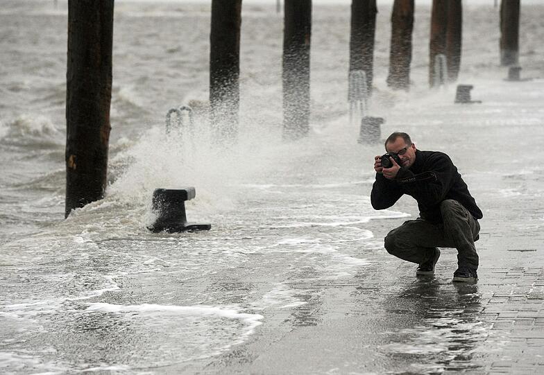 Für das private Fotoalbum: Bei schweren Sturmböen fotografiert ein Mann im Fischereihafen von Norden-Norddeich (Niedersachsen)