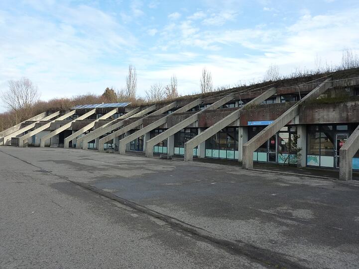 Neben der Tribüne ist das flache Schullandheim. In diesem Komplex sind auch Organisationsräume für Regatten und Vereinsräume der Rudergesellschaft München und des Schleißheimer Ruderclubs. Das Dach ist begrünt - und undicht.