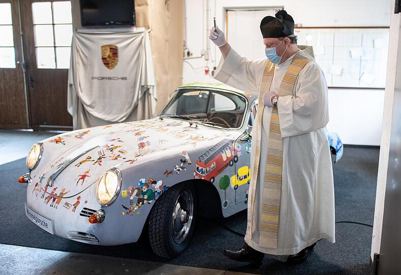 Manfred Wurzer, katholischer Pfarrer in Egling, segnet den Porsche in der Werkstatt von KFZ-Meister Freinecker.