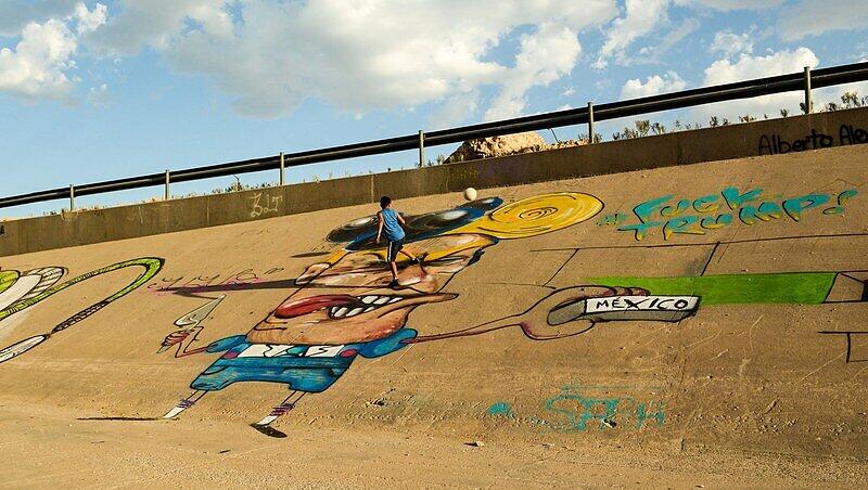 Die Kinder scheren sich nicht um diese etwas lächerlich wirkende Figur aus der Politik. Sie spielen auf der riesigen Graffiti-Karikatur an der Grenze zwischen Mexiko und den USA Fußball. Die Kinder scheren sich nicht um diese etwas lächerlich wirkende Figur aus der Politik. Sie spielen auf der riesigen Graffiti-Karikatur an der Grenze zwischen Mexiko und den USA Fußball.