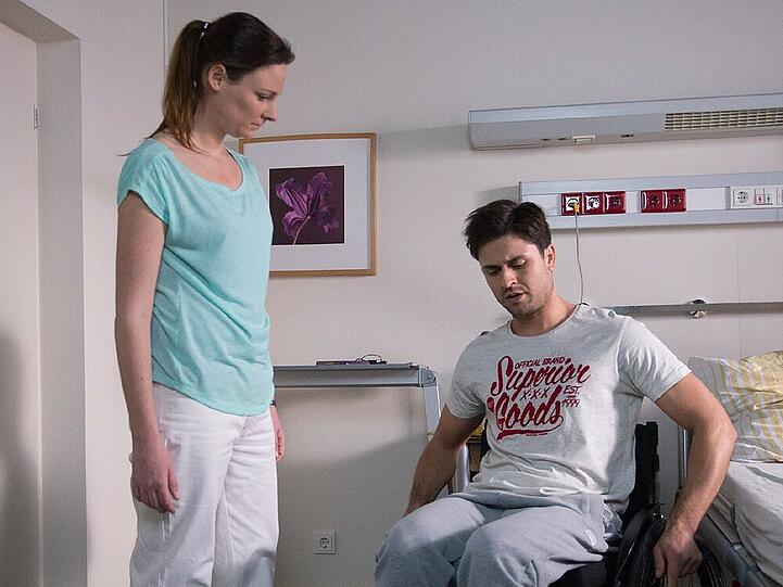 Paco (Milos Vukovic) macht sich mit Hilfe einer Therapeutin (Komparsin) beklommen mit dem Rollstuhl vertraut.