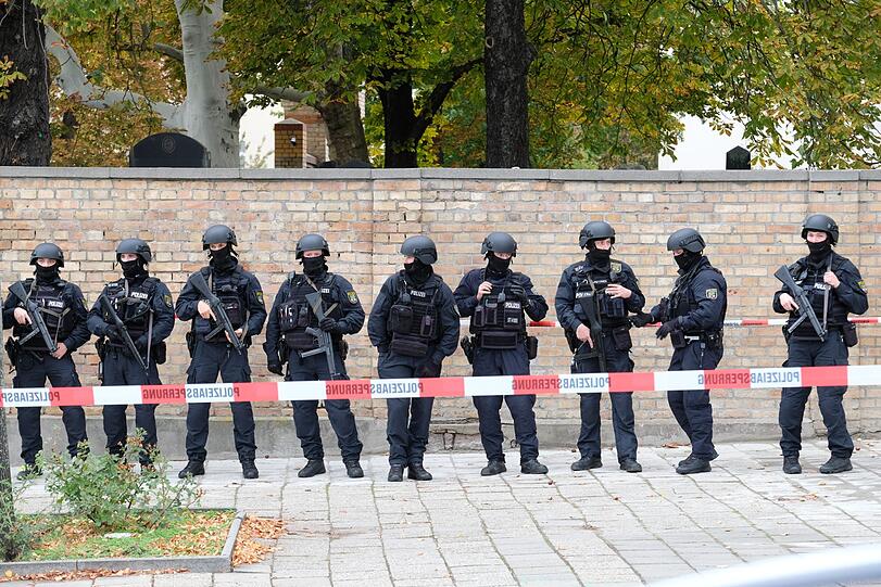 Polizisten mit Schutzhelmen sichern den Bereich am jüdischen Friedhof.