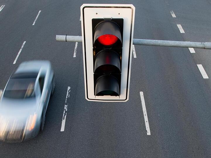 Ein Auto fährt an einer roten Ampel vorbei. Foto: Julian Stratenschulte/dpa/Symbolbild