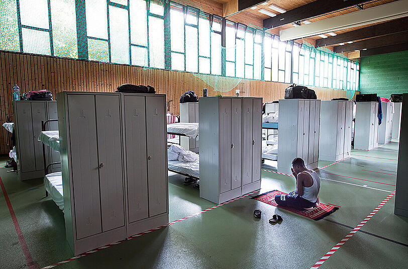 Ein Mann betet am 24.07.2015 in einer zur Flüchtlingsunterkunft umfunktionierte Turnhalle im Münchner Stadtteil Trudering (Bayern). Das Motiv des dpa-Fotografen Peter Kneffel wurde zum Siegerfoto in der Kategorie "Bayern Land & Leute" beim Pressefoto Bayern 2015 gekürt.