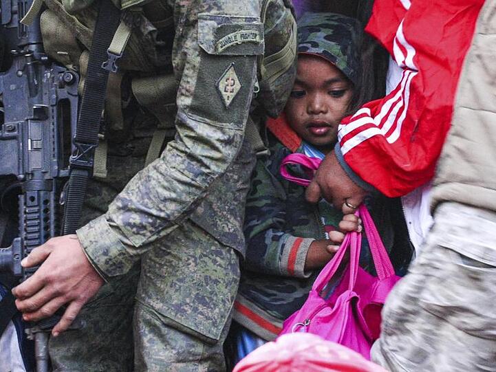 Ein Mädchen aus der Stadt Batangas wartet gemeinsam mit anderen Bewohnern auf ein Militärfahrzeug, das sie zu einem Evakuierungszentrum bringen soll.