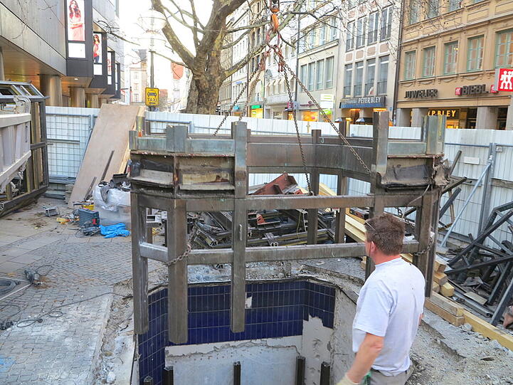 Mit dem Kran heben die Bauarbeiter den alten Aufzug zwischen Sperrengeschoss und Oberfläche am Marienplatz aus den Fugen.