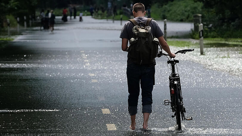 Ein Passant geht in Hannover über eine überschwemmte Straße. Der Juli ist in ganz Deutschland viel zu nass gewesen.