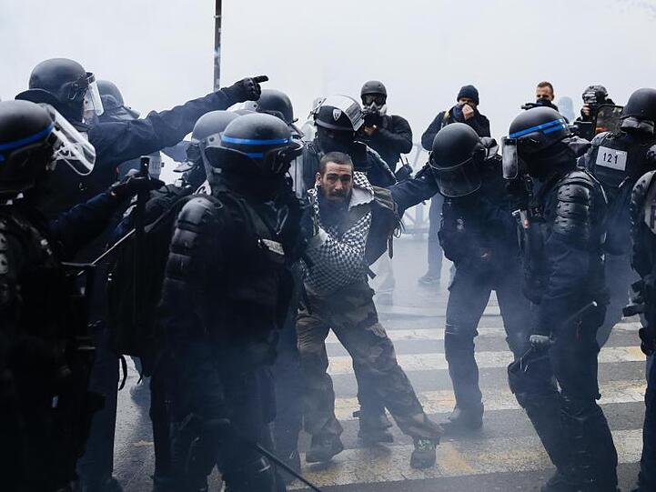 Ein Demonstrant wird in Paris von Polizisten festgehalten.
