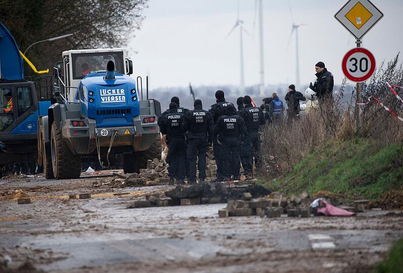 Schwere Räumfahrzeuge entfernen im Beisein der Polizei die von Klimaaktivisten errichteten Barrikaden.