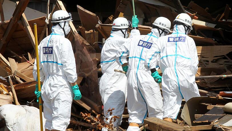 Makabre Aufgabe: Japanische Soldaten suchen in den Trümmern nach Leichen. Makabre Aufgabe: Japanische Soldaten suchen in den Trümmern nach Leichen.