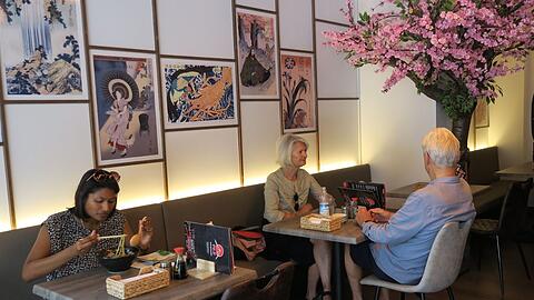 Kunstdrucke und der in kräftigem Pink blühende (Kunst-)Kirschbaum. Blick ins Fuji am Kurfürstenplatz.
