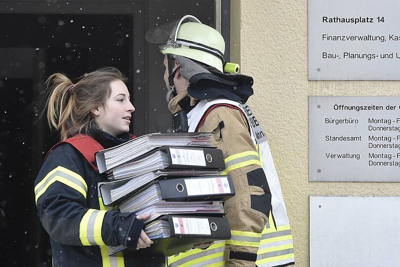 Einsatzkräfte der Feuerwehr bringen Unterlagen aus dem Erdgeschoss in Sicherheit.