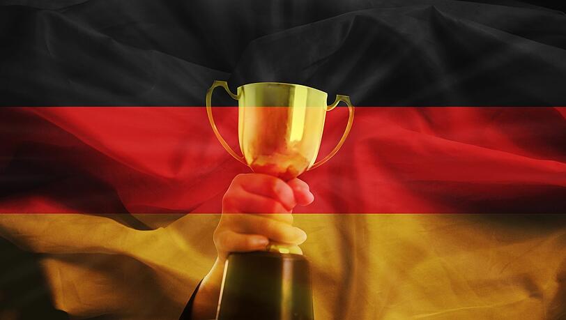 Ein Pokal auf dem Hintergrund einer Deutschland-Flagge. Kann unsere Demokratie für den Westen voranschreiten?