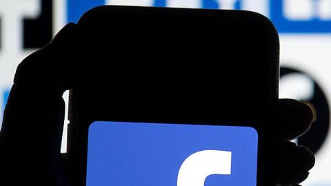 Das Facebook-Logo ist auf dem Display eines Mobiltelefon zu sehen.