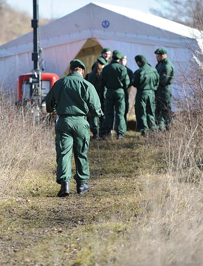 Polizisten stehen am Montag vor einem Zelt der Spurensicherung am Ufer des Rathei-Weihers zwischen Zell und Karlshuld.